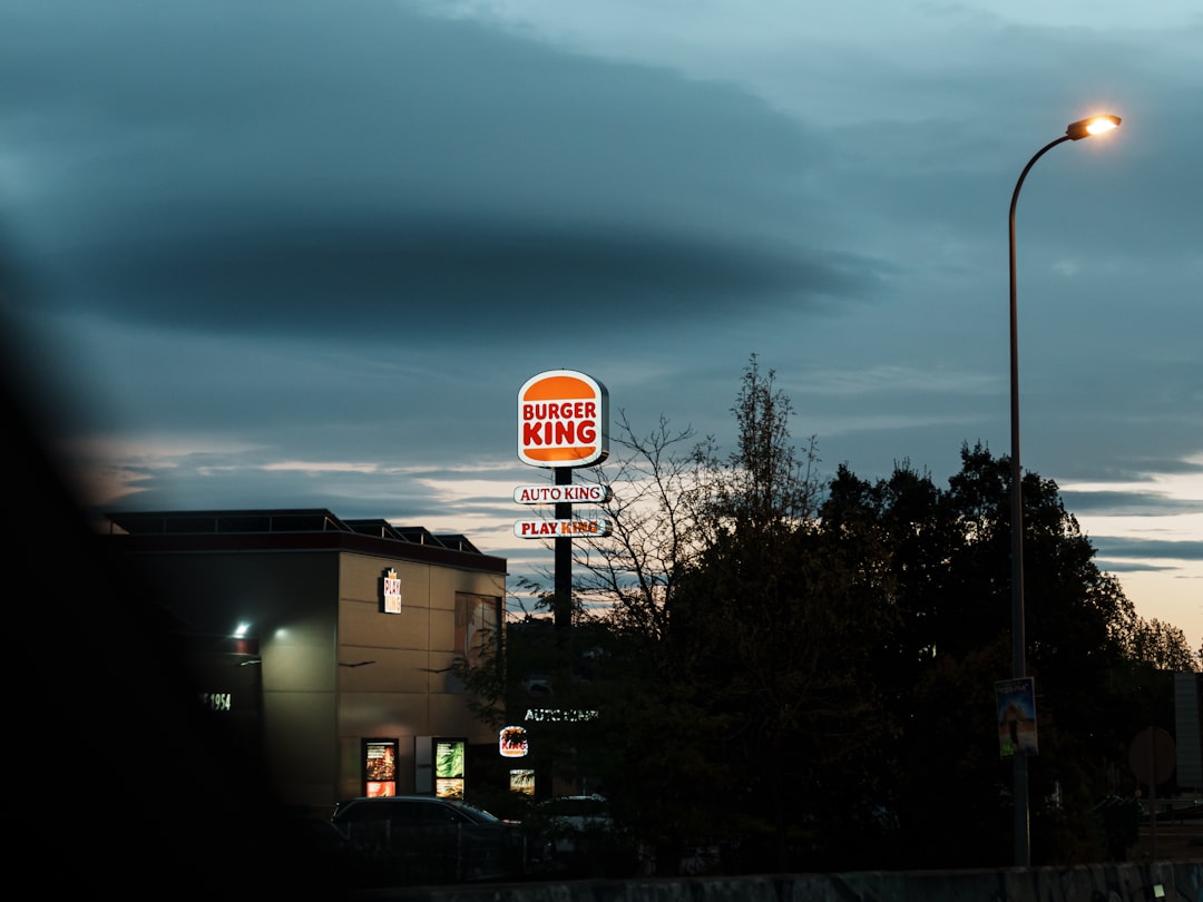 Illuminated burger king sign against a dark evening sky.