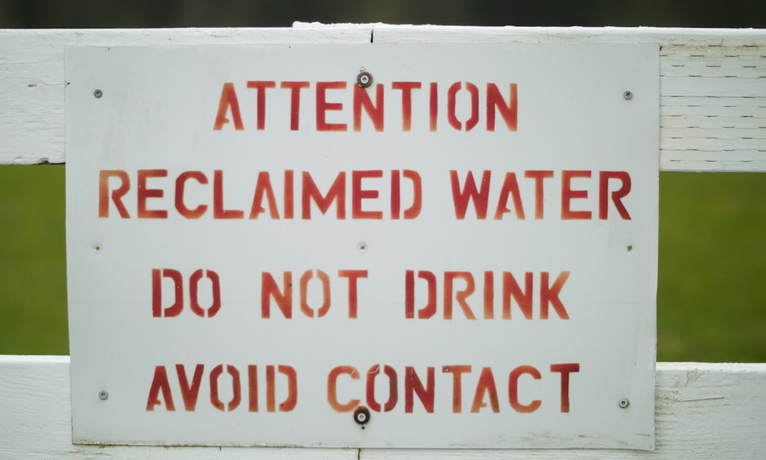 a sign on a white fence warning people to not drink