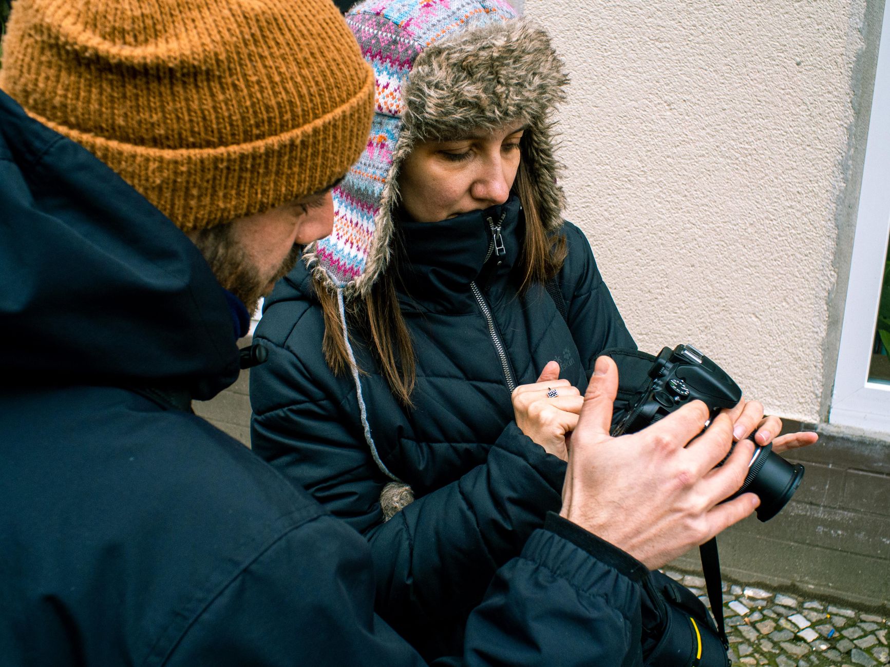 Two warmly dressed photographers reviewing camera settings on a cold day in Berlin.
