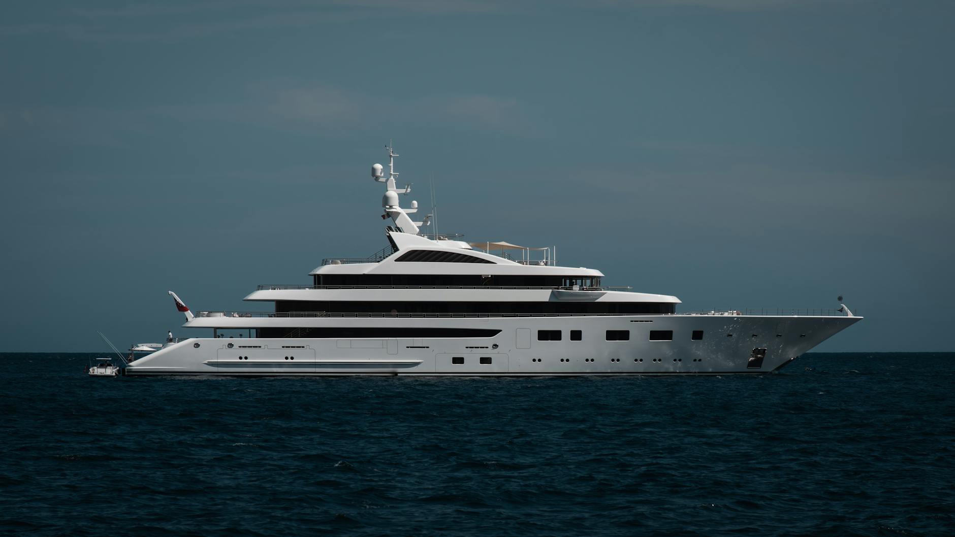 A sleek luxury yacht cruising on the calm open ocean under a clear sky.
