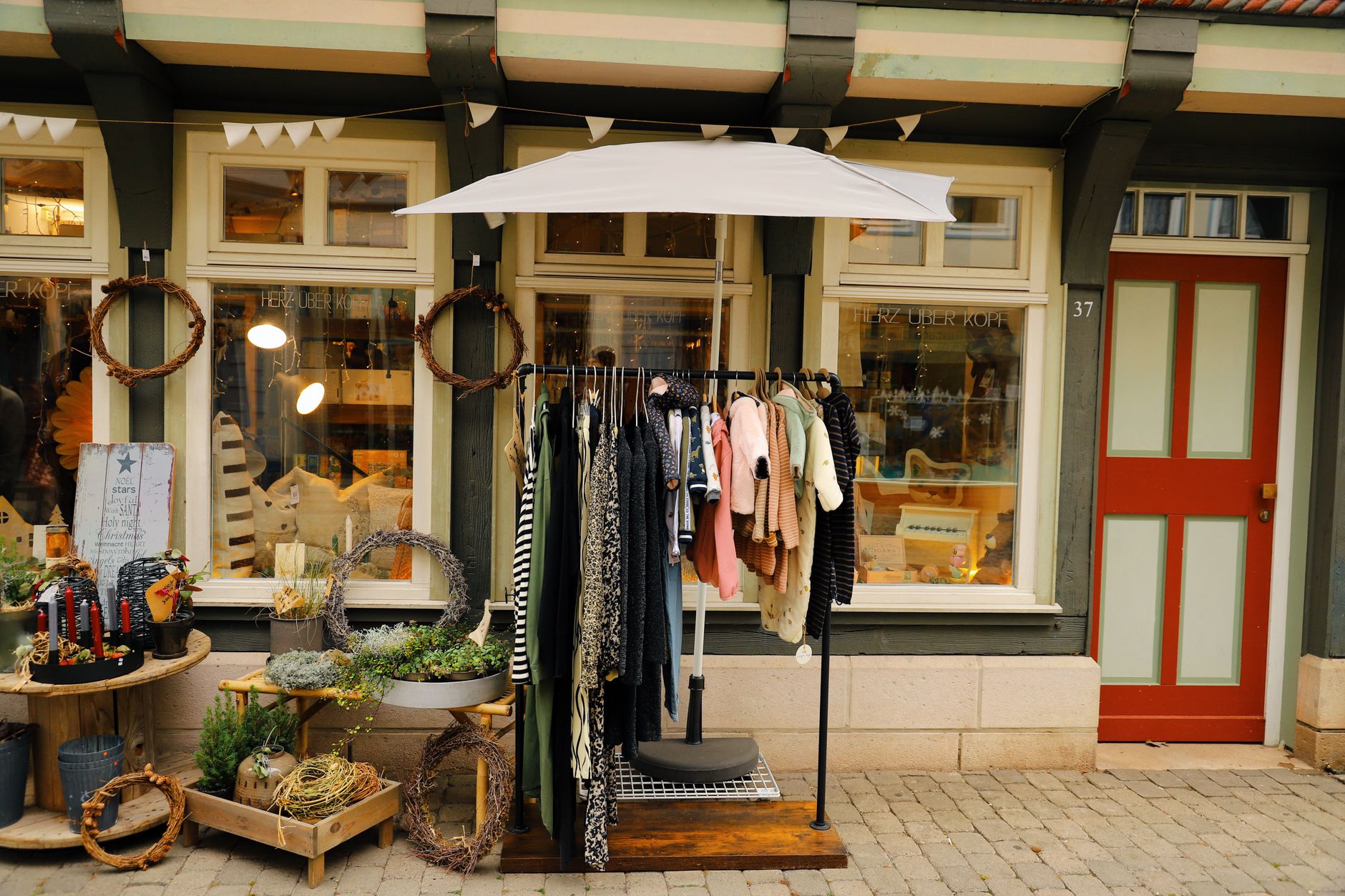 Charming timber-framed storefront in Hann. Münden with clothing and decor display.