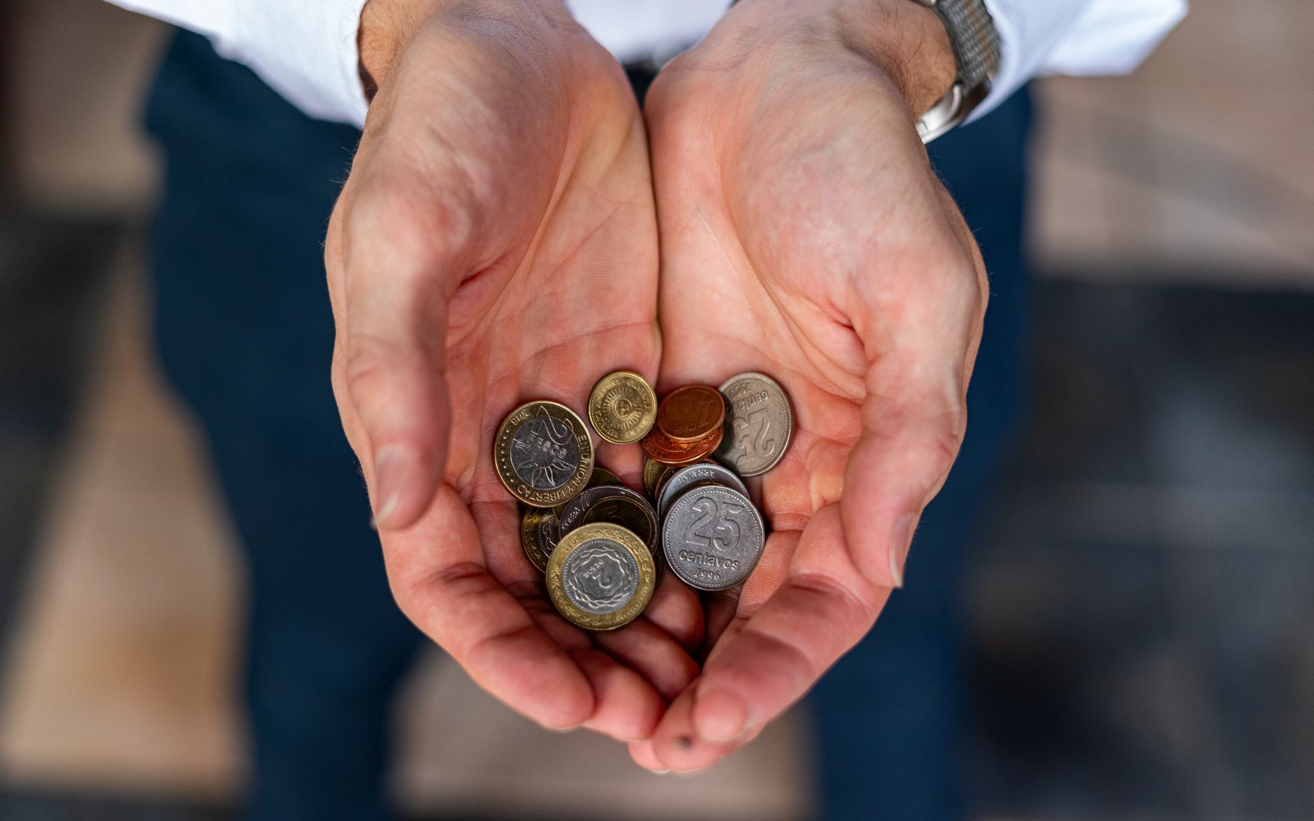 Close-up of hands holding Argentine coins, showcasing currency detail in Buenos Aires.