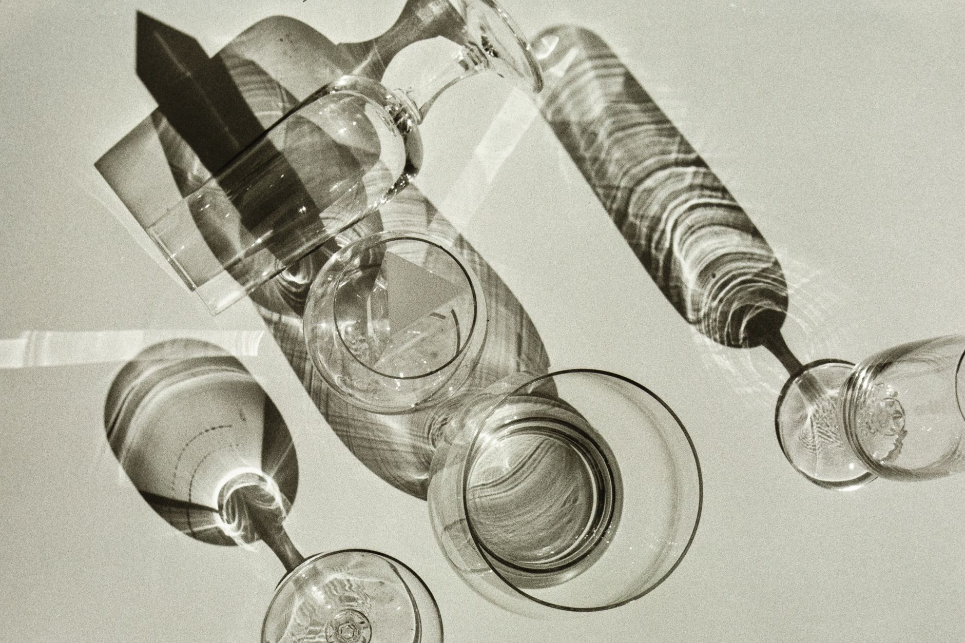 Elegant shadows of glassware casting patterns on a surface, showcasing a play of light and art.