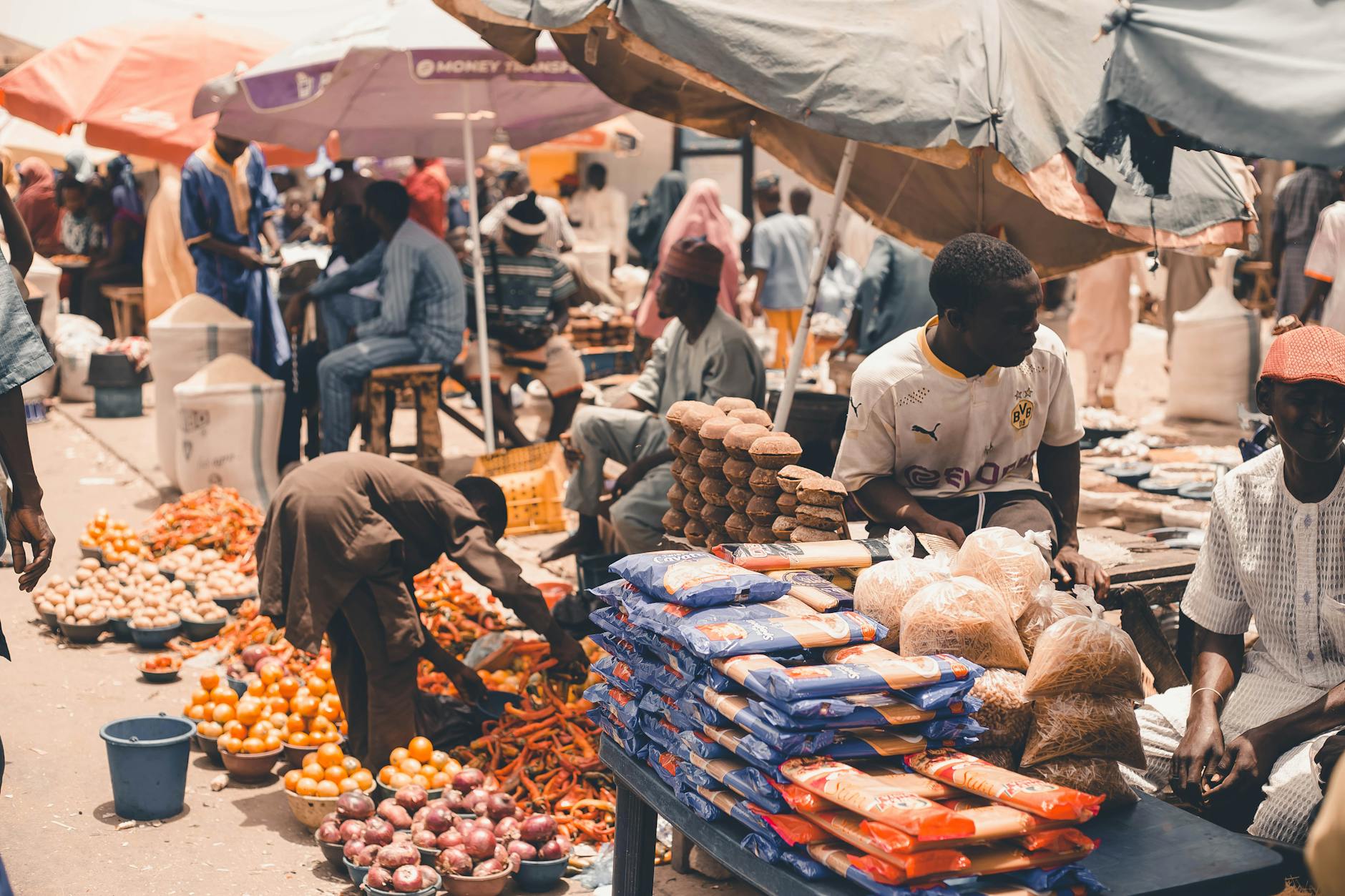 Lively market scene showcasing fresh produce and vendors under colorful umbrellas, capturing the essence of local trade.