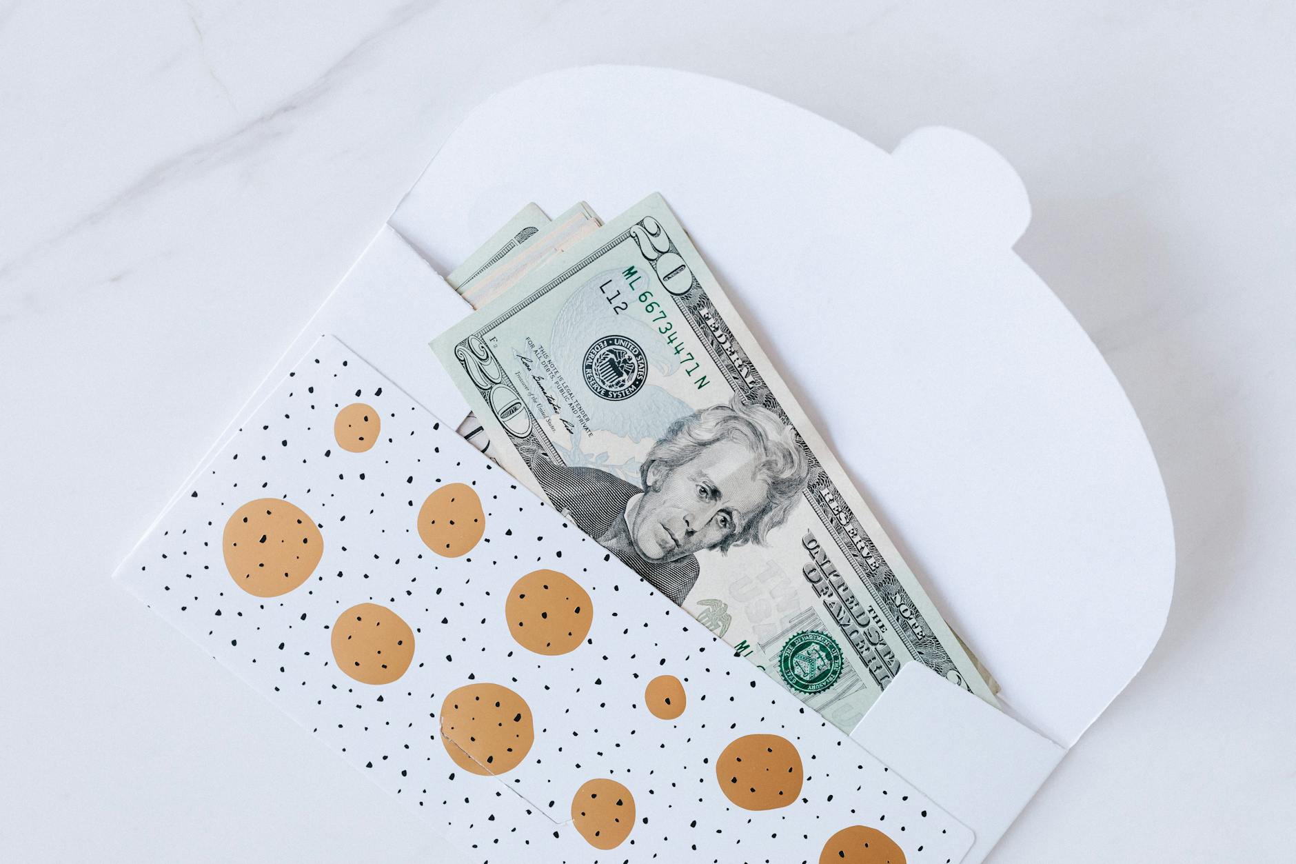Top view of open carton money envelope with pile of paper money for birthday gift on white table