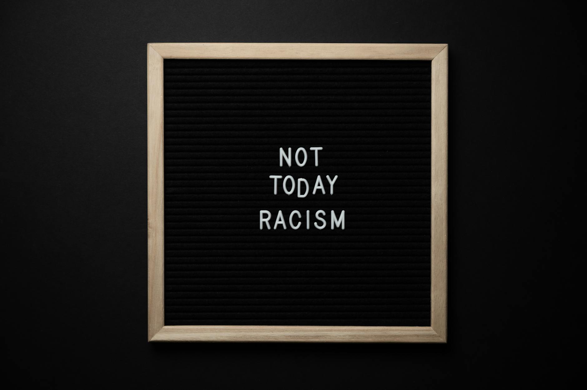 Overhead view of phrase Not Today Racism on square framed signboard on black background