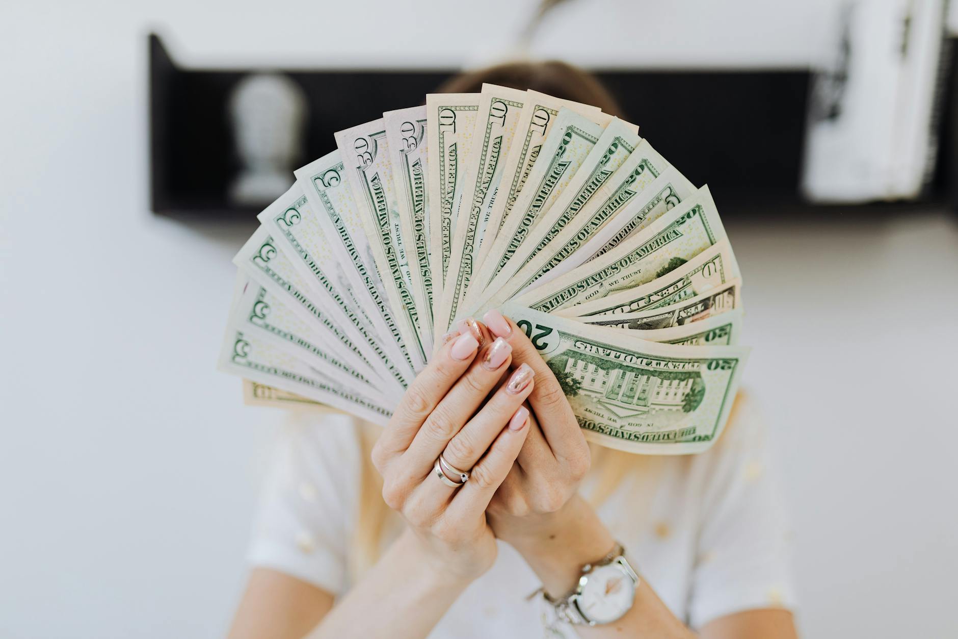 Close-up of hands holding a fan of US dollar bills, showcasing financial abundance.