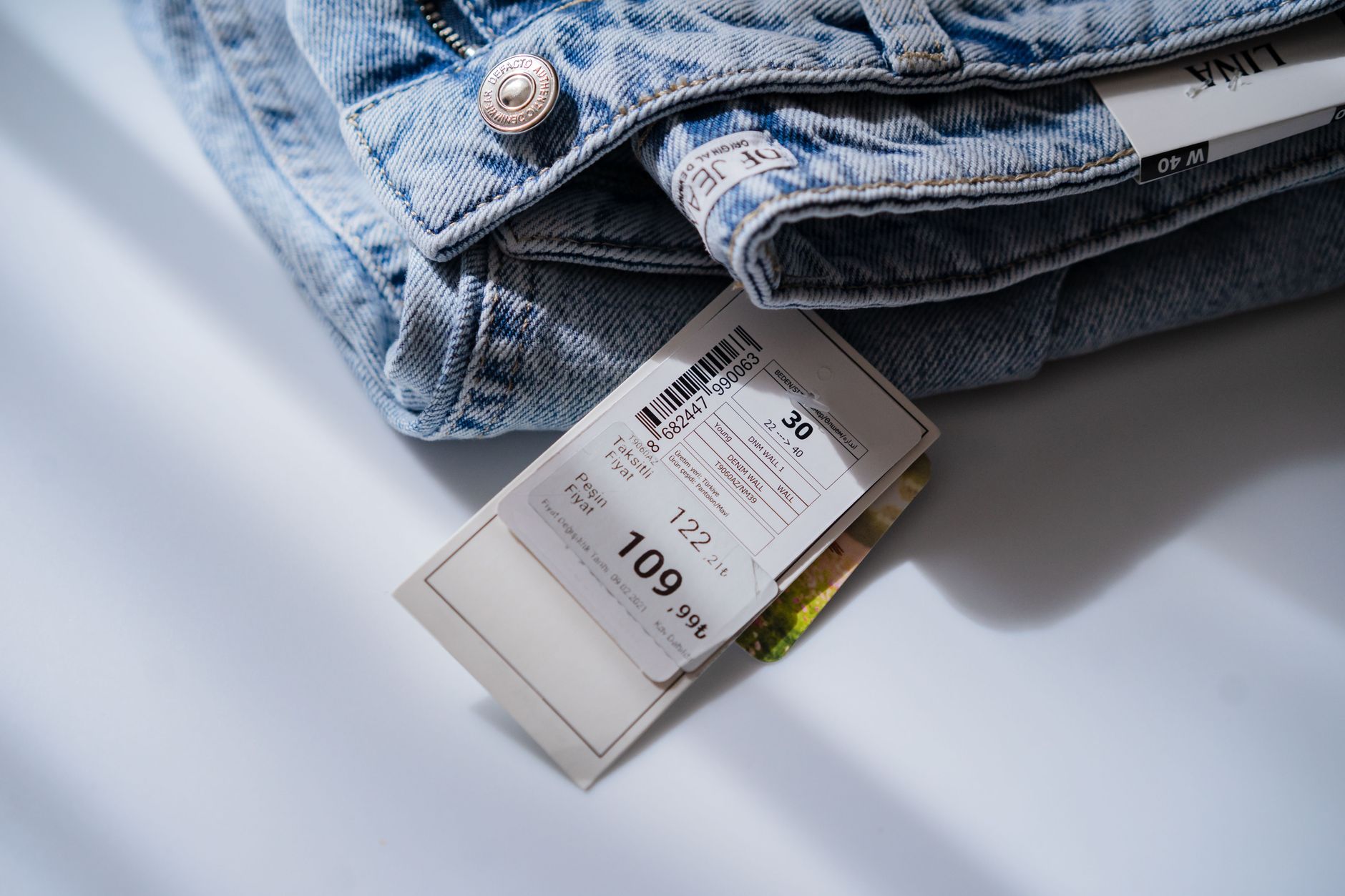 From above of blue jeans with retail price and size label placed on white table