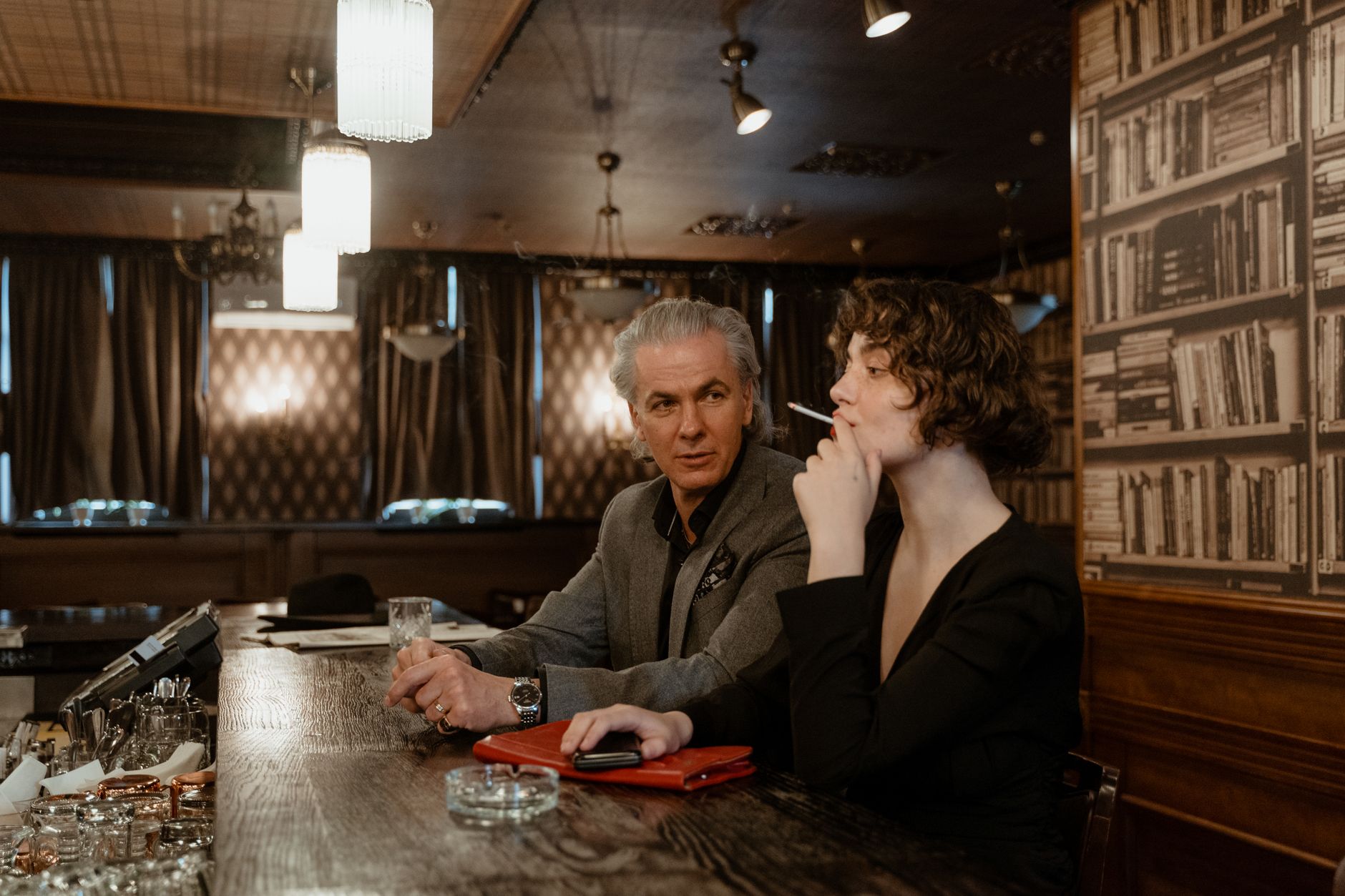 Elegant scene of a mature man and woman enjoying drinks at a stylish bar.