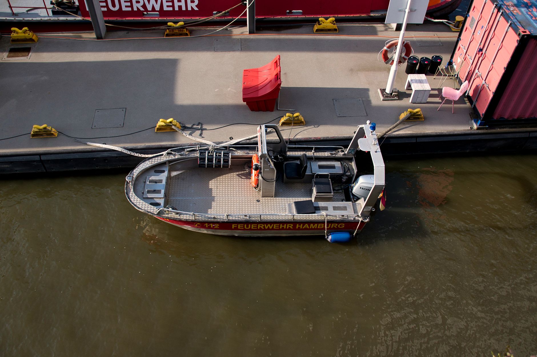 A firefighting boat docked at Hamburg harbor under sunlight, ready for emergencies.